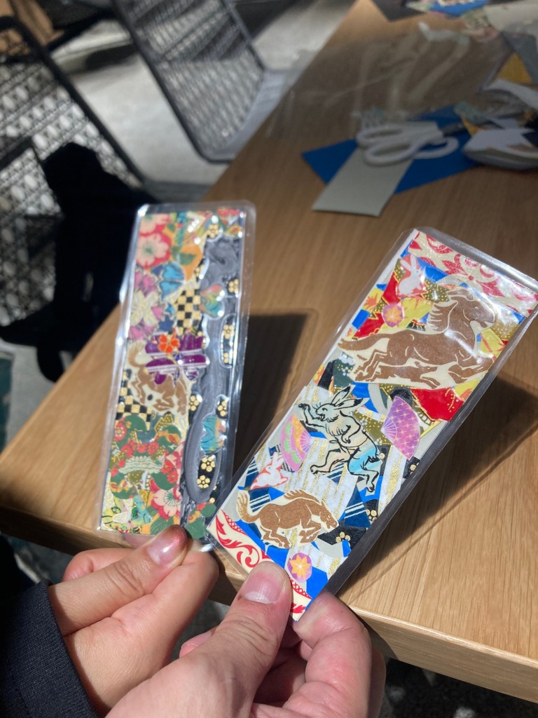 Two collage bookmarks held up by a participant