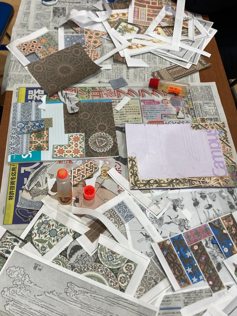 A table covered with printed collage materials, scissors and glue